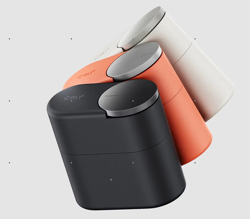 The CMF Clip Pro charging case in dark grey, orange and white, each with the Smart Dial on top.